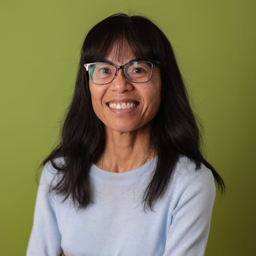 Dr. Duong standing and smiling in a blue sweater.