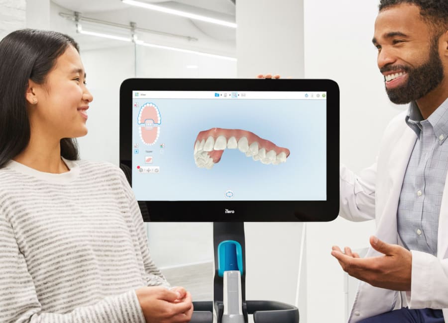 A male dentist shows a digital image of dental impressions to a woman.